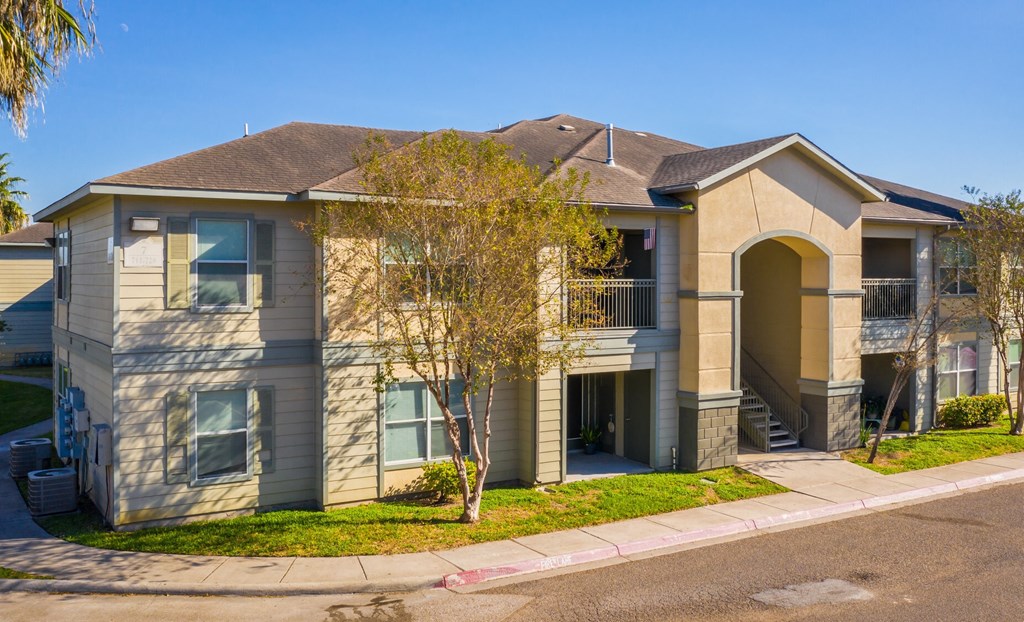 a house with a sidewalk and a tree in front of it