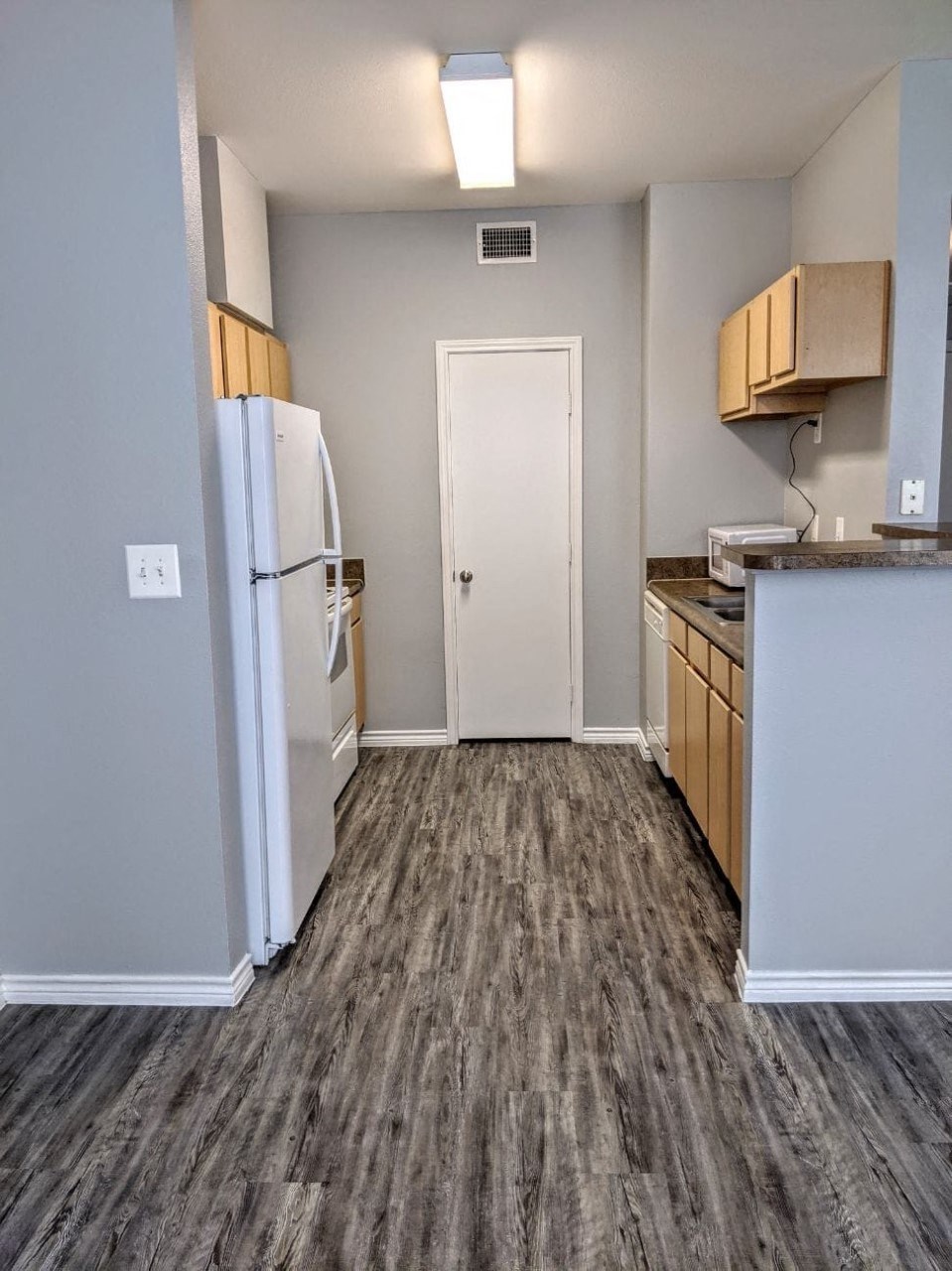 an empty kitchen with a refrigerator and a sink