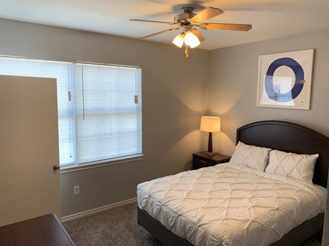 a bedroom with a bed and a ceiling fan and a window