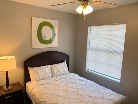 a bedroom with a bed and a ceiling fan and a window
