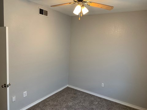 a bedroom with a ceiling fan and gray walls