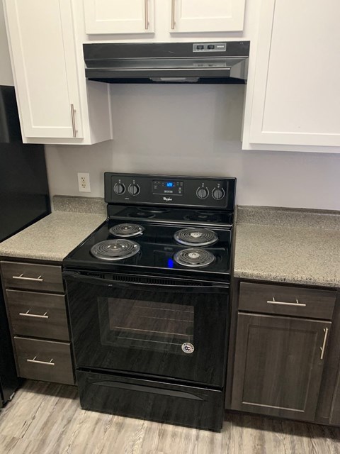 a black stove in a kitchen with white cabinets