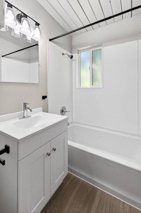 Newly remodeled modern style bathroom with a sink, mirror, and bathtub at Horizon Park Apartments