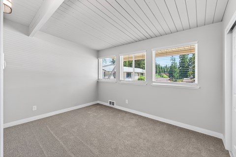 Bedroom a carpeted floor and a window showing a view of trees and a house at Horizon Park Apartments