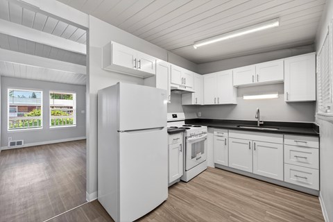 A white kitchen with a refrigerator, stove, and cabinets.