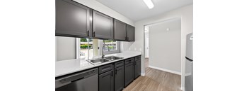 A kitchen with black cabinets and a white countertop.