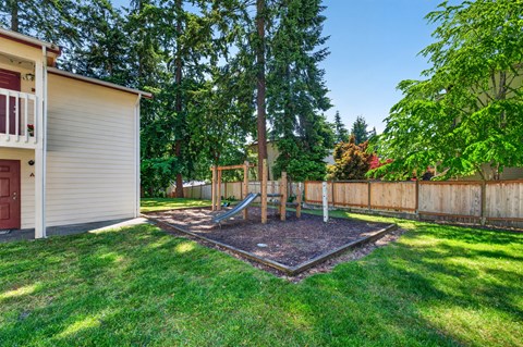 A backyard with a playground and a fence.