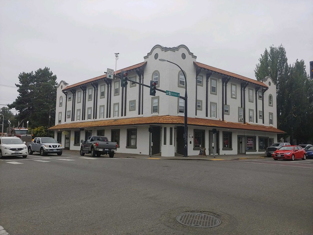 a white building with a brown roof and cars parked in front of it