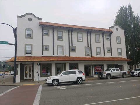 a building on the corner of a street with cars parked in front of it