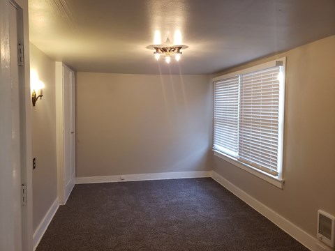 a living room with a large window and a ceiling fan
