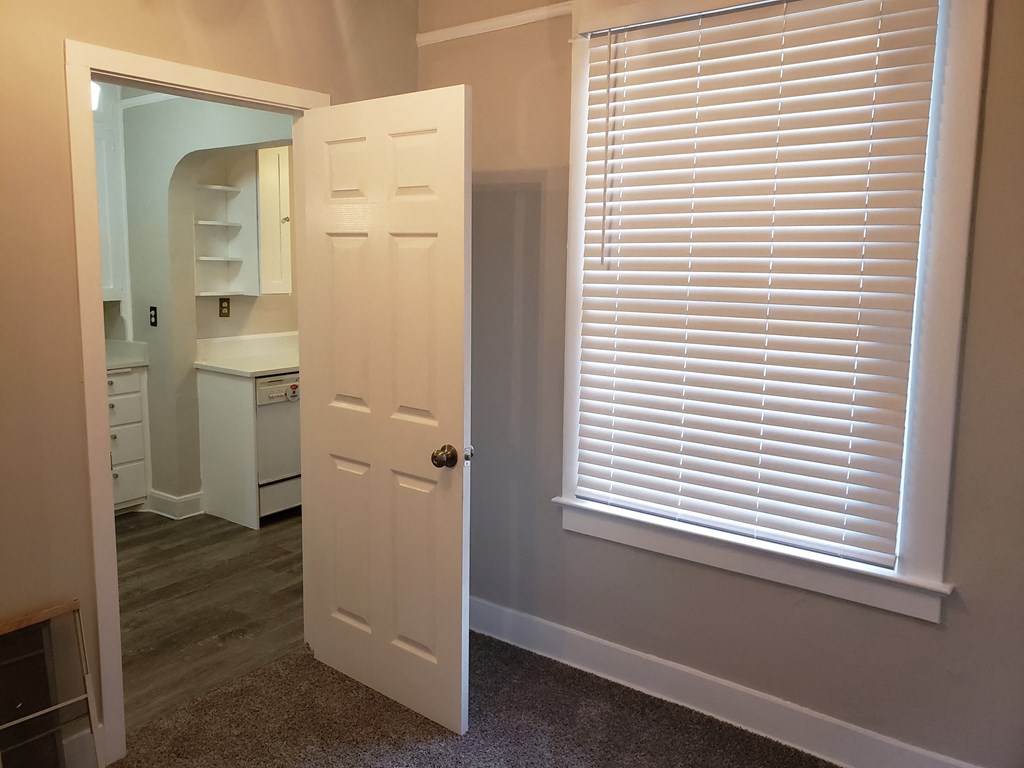 a small room with a door and a window and a sink