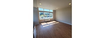 A room with wooden flooring and a large window.