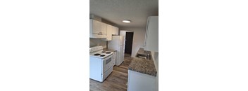 A kitchen with a granite countertop and white appliances.