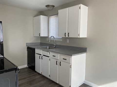 a kitchen with white cabinets and a sink and a window