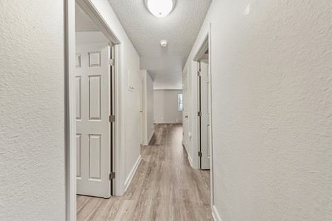 A long hallway with white walls and wood flooring.