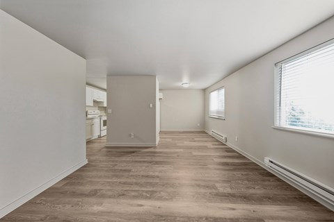 A room with a wood floor and a window with blinds.