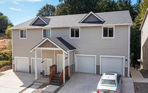 A house with a grey roof and a car parked in front.