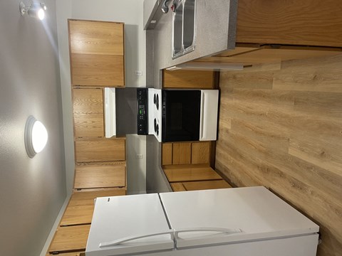 A white refrigerator in a kitchen with wooden cabinets and a wooden wall.