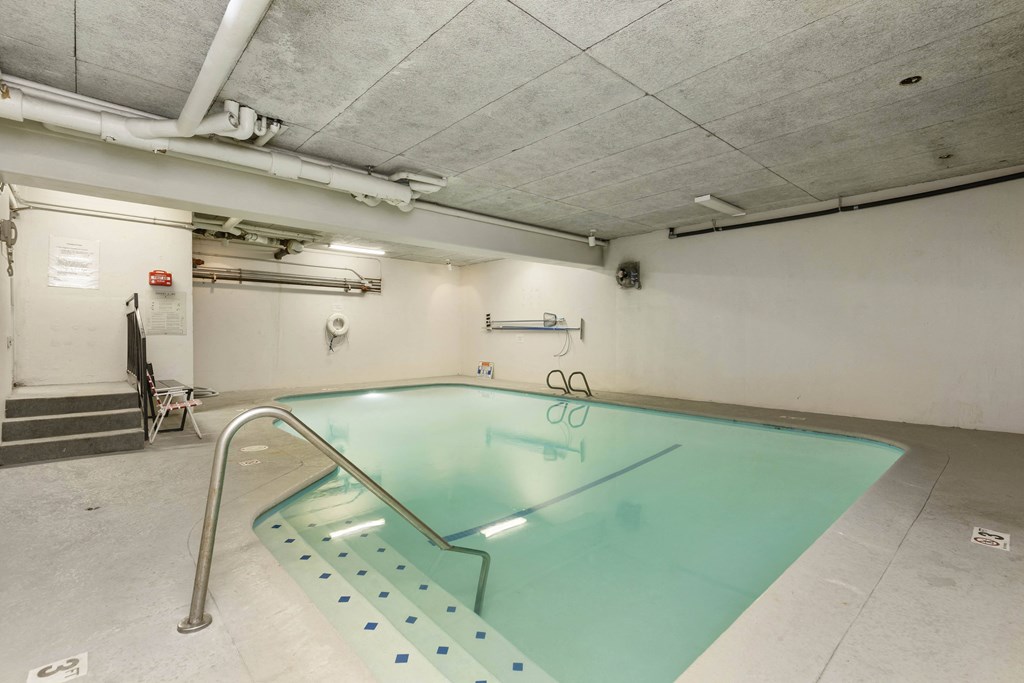 an indoor swimming pool in a building with white walls and concrete floors