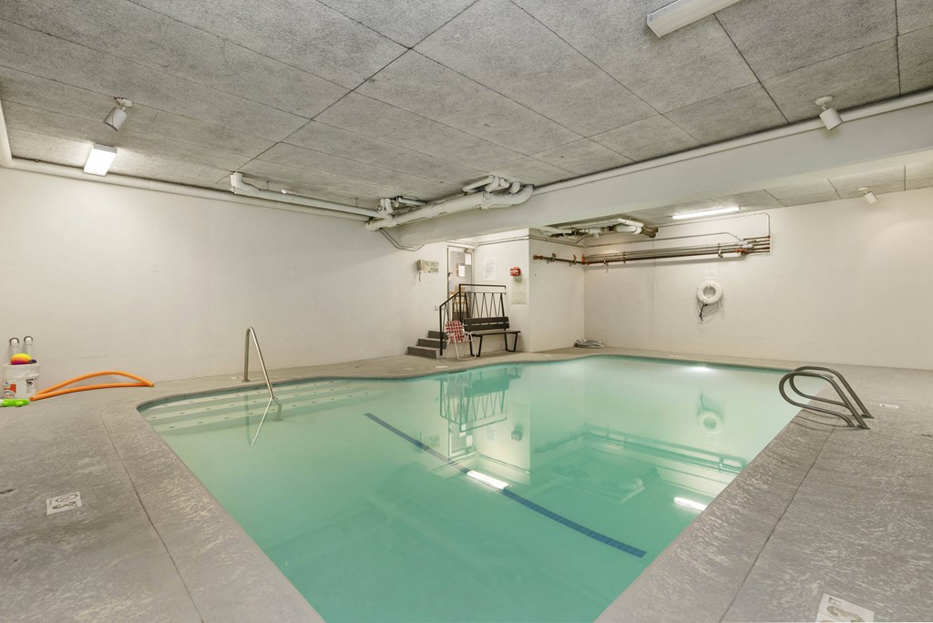 a swimming pool in a room with white walls and concrete floors