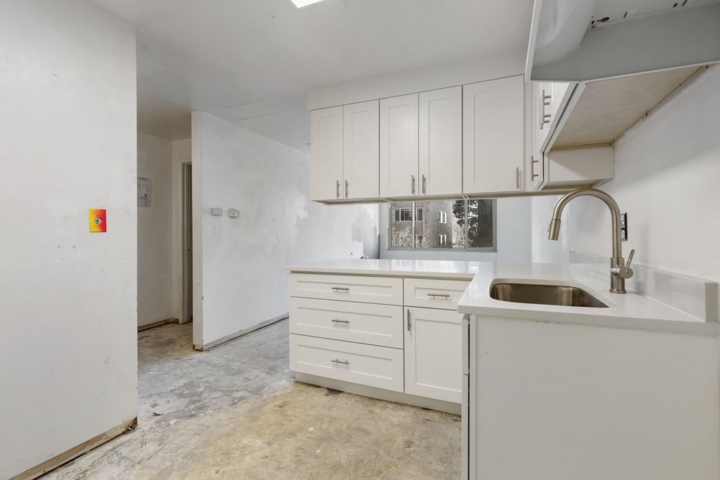 an empty kitchen with white cabinets and a sink