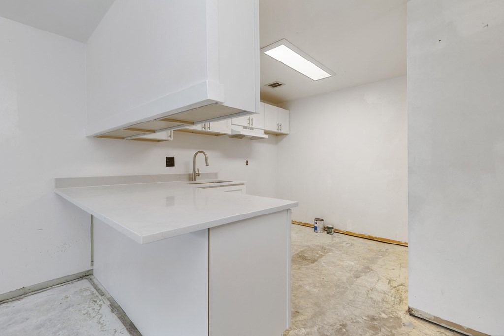 the kitchen is being remodeled with white cabinets and white counter tops and a sink