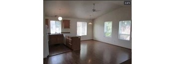 an empty living room and kitchen with wood floors