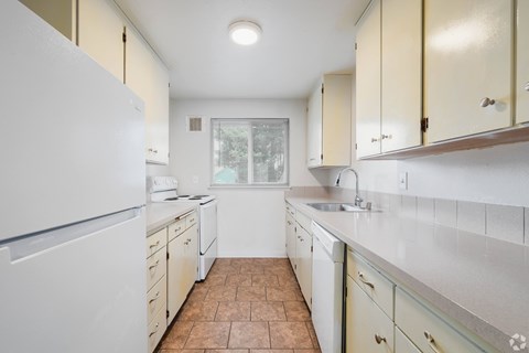 A kitchen with a white refrigerator and white cabinets.