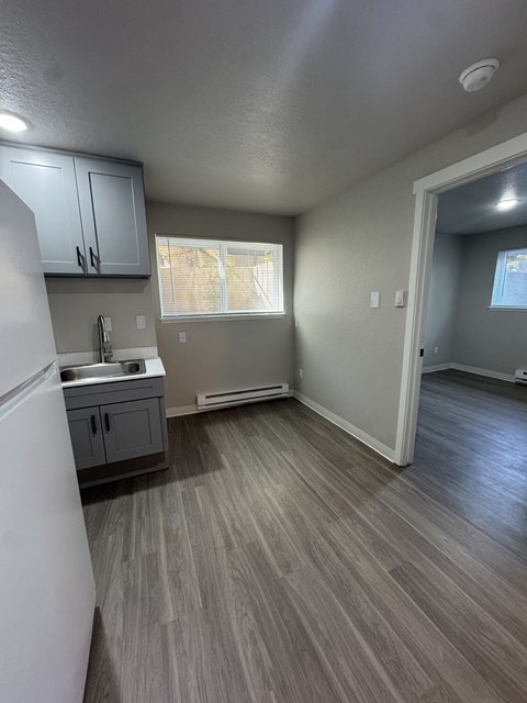 A kitchen with a white refrigerator and grey cabinets.