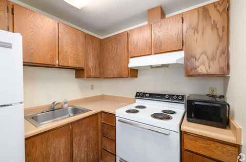 A kitchen with a white stove and wooden cabinets.