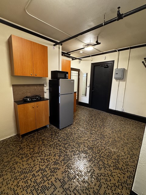 A kitchen with a black fridge and wooden cabinets.