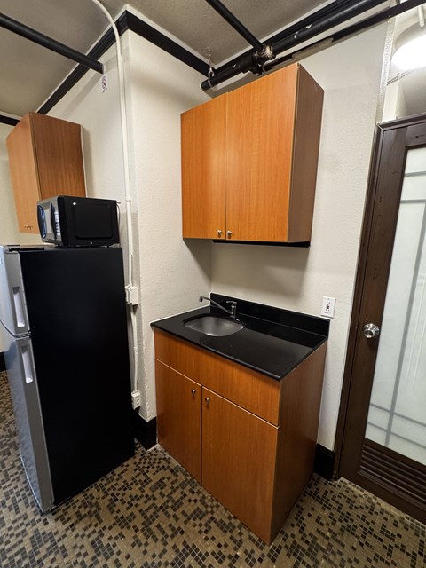 A small kitchen with a black fridge and a black counter top.