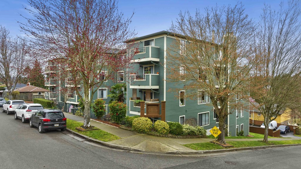 a green apartment building with cars parked in front of it