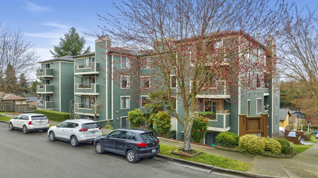 a large green apartment building with cars parked in front