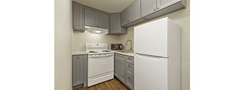 A white refrigerator is in a kitchen with grey cabinets.