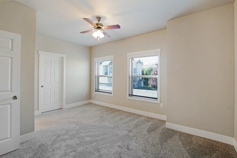 Bedroom with ceiling fan, closet, windows, and carpet at Hearthstone Apartments