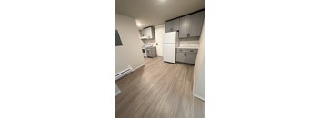 A kitchen with white appliances and wooden floors.