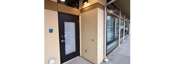 A black door with a window is on the left and a white pipe is on the right.