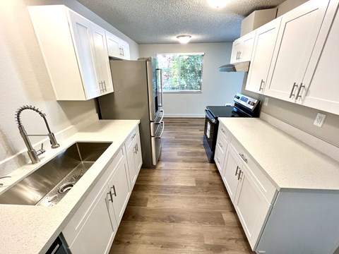 A kitchen with white cabinets and a wooden floor.