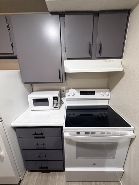 A white microwave oven is on a countertop above a stove.