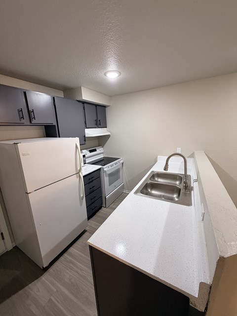 A white refrigerator is in a kitchen with a white counter.