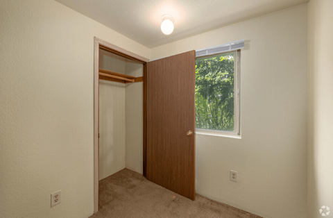 A room with a brown door and a window with a view of trees.
