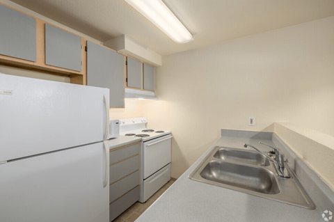 A white refrigerator sits next to a sink in a kitchen.