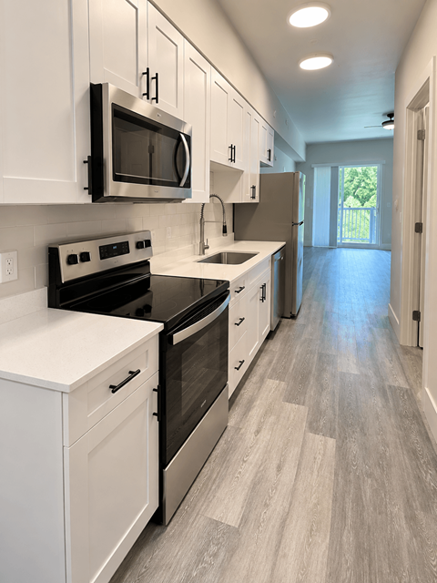 A kitchen with white cabinets and a black microwave.