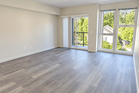 A room with light wood flooring and sliding glass doors.