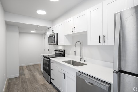 A modern kitchen with white cabinets and stainless steel appliances.