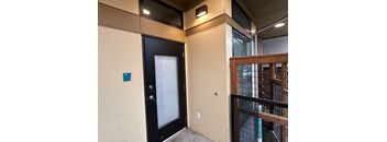 A black door with a window and a blue square on the wall.