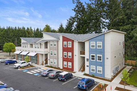 A parking lot with cars and a building with red, white and blue colors.