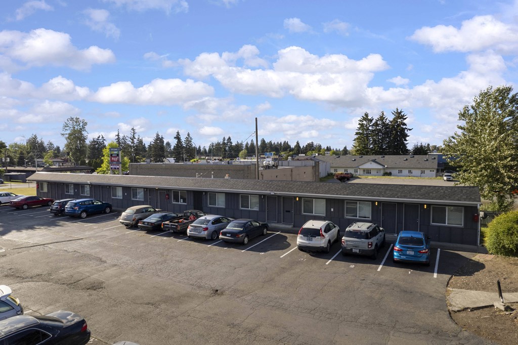 an empty parking lot with cars in front of a building