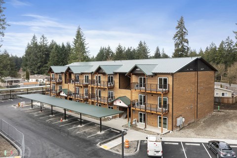 A large building with a green roof and a parking lot in front.